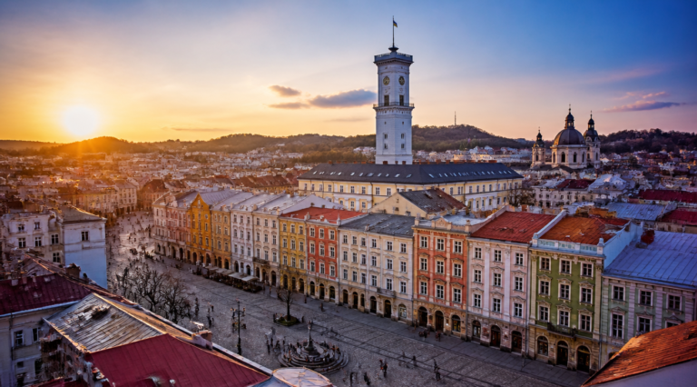 A stunning panoramic view of Lviv old town in Ukraine at golden hour, showing the historic Rynok Square with its colorful Renaissance and Baroque buildings, the tall Ratusha town hall tower in the center, red-tiled rooftops, cobblestone streets, and the silhouette of the Latin Cathedral. Warm sunset light bathes the central European architecture in golden tones, with a few locals and tourists walking through the square. Photorealistic, high resolution, travel photography style, vibrant colors, atmospheric lighting.